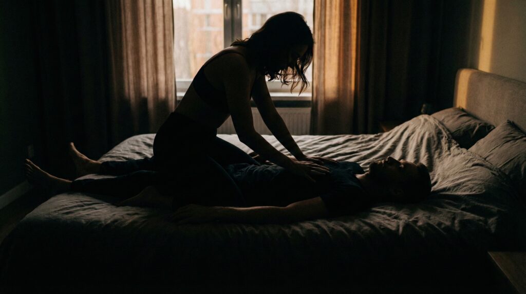 A shadowed silhouette of a couple in bed, with a woman leaning forward over a man, conveying tension, control, and intimacy.